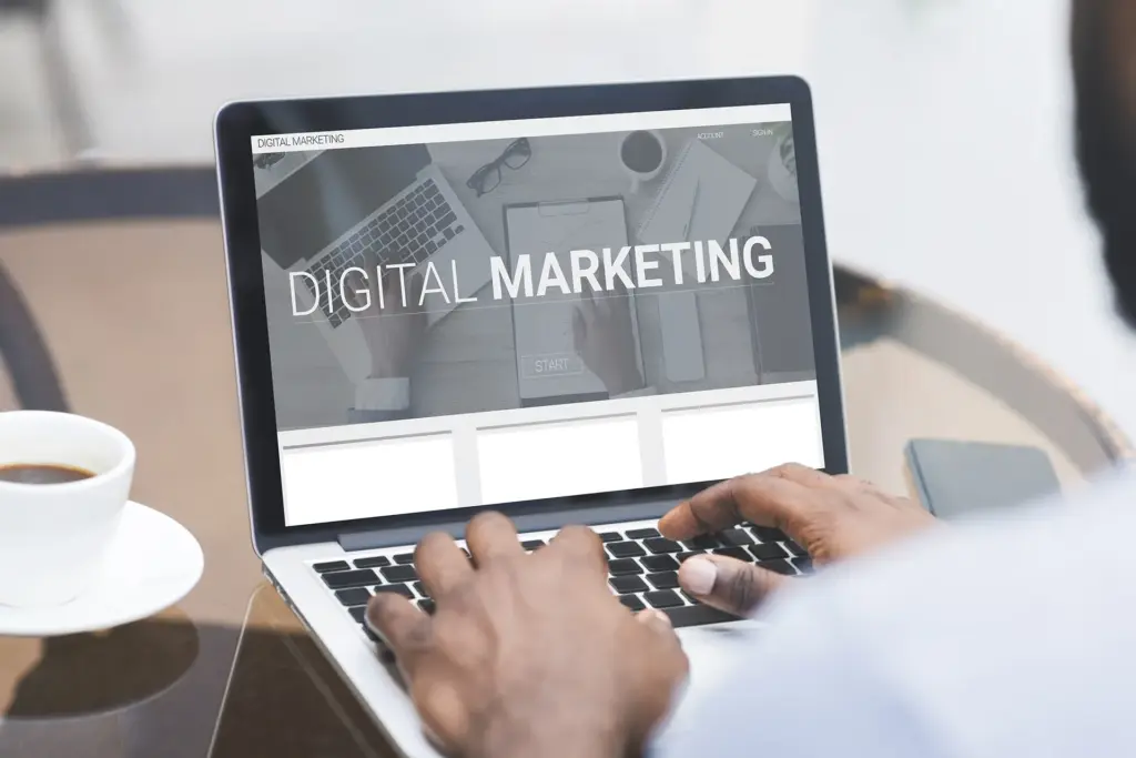 Man working on laptop in cafe with Digital marketing on the screen