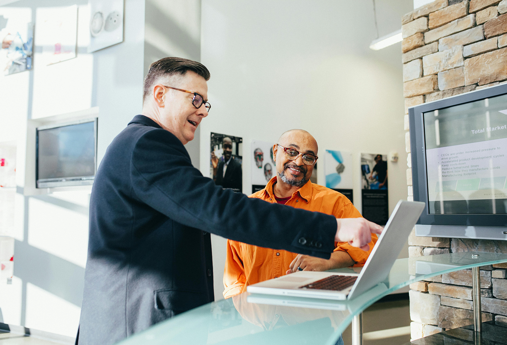Smiling Businessman pointing to laptop to highlight information to client next to him