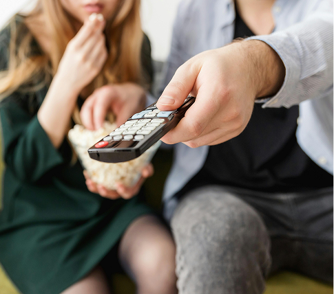 Close up couple eating popcorn and selecting show on TV with remote