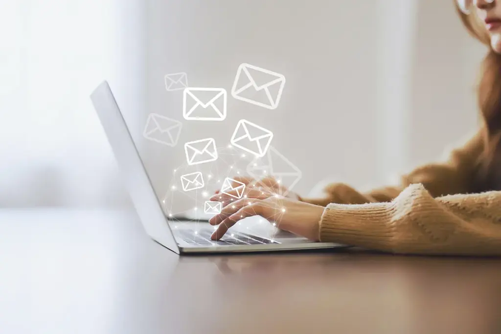 Woman's hands on laptop with several email envelopes overlayed.