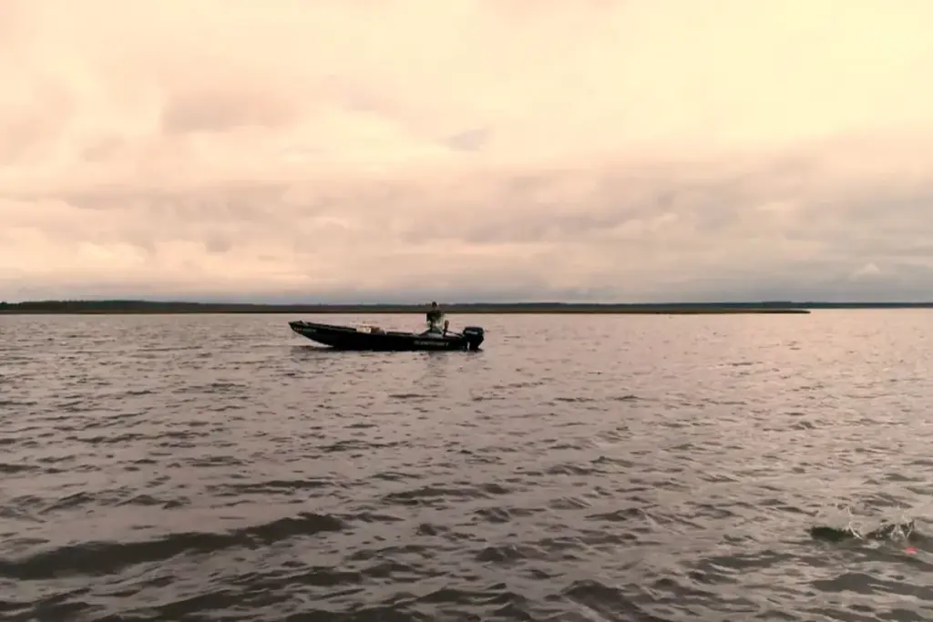 Man boating on lake using Nelson Outdoors fishing gear