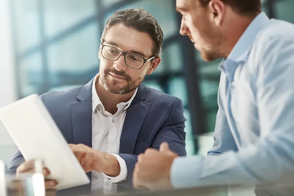 Two men looking at a tablet to discuss campaign results.